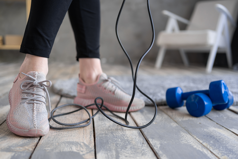 Woman standing with jump rope and dumbbells